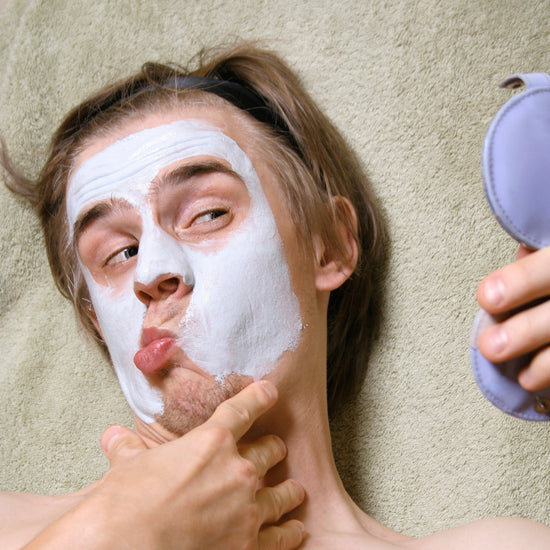 Person applying a facial mask with a purple container on a beige towel background